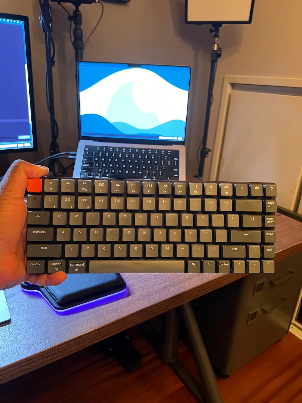 Photo du Keychron K6 dans ma main en face de mon MacBook Pro