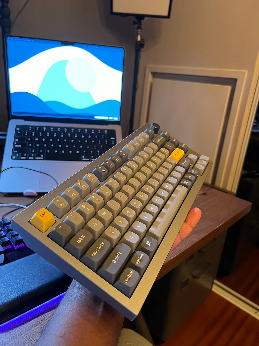 Photo du Keychron Q1 de profil, dans ma main, face à mon MacBook Pro